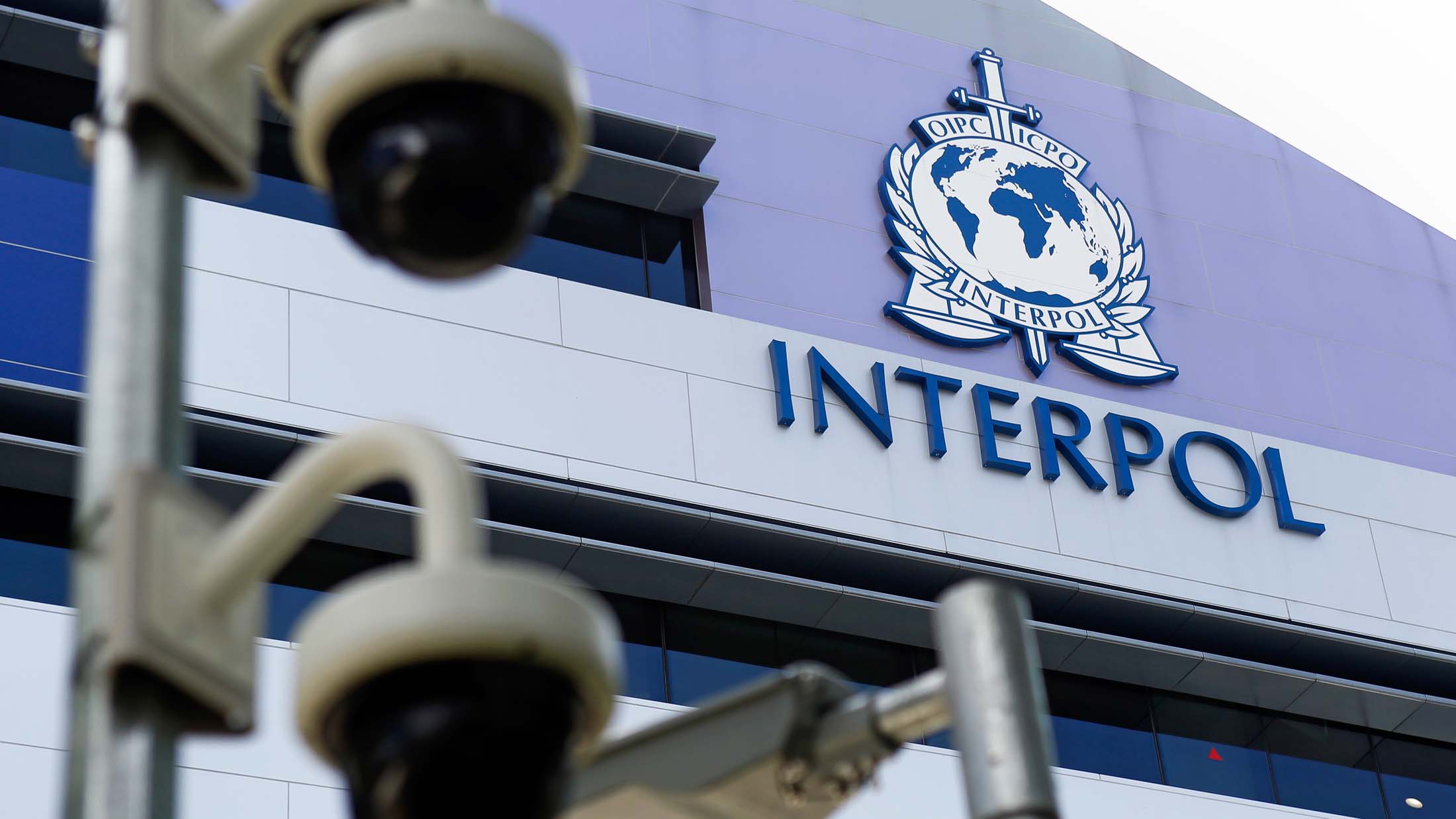 epa04703664 Security cameras pictured against the Interpol logo on the Interpol Global Complex for Innovation building (IGCI) in Singapore, 14 April 2015. Interpol's first digital crime centre was officially opened in Singapore on 13 April 2015. Complementing its headquarters in Lyon, the Interpol Global Complex for Innovation (ICGI) will support international policing efforts against cybercrime, as well as research and capacity building in online security. EPA/WALLACE WOON